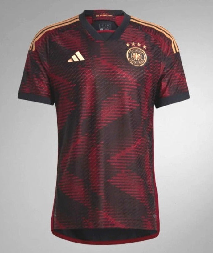 Detalle en alta resolución del logo de Adidas en transfer térmico dorado sobre el patrón técnico del jersey Alemania 2022 Away.