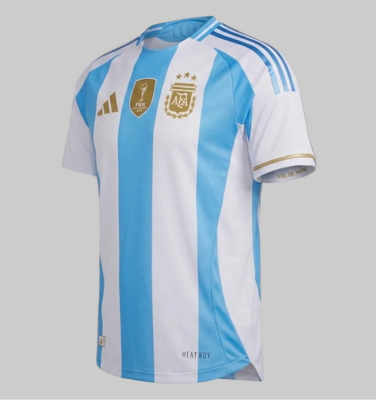 Vista angulada del jersey de local Adidas Argentina Authentic Match 2024 (IP8388), presentada en condición 'Deadstock' inmaculada sobre un fondo de estudio gris neutro. El jersey muestra los icónicos bastones albicelestes con todas las insignias oficiales, incluyendo el escudo de la AFA en dorado con tres estrellas, el logo de Adidas en dorado y el parche central dorado de Campeón Mundial de la FIFA 2022, disponible en Futbol90MX