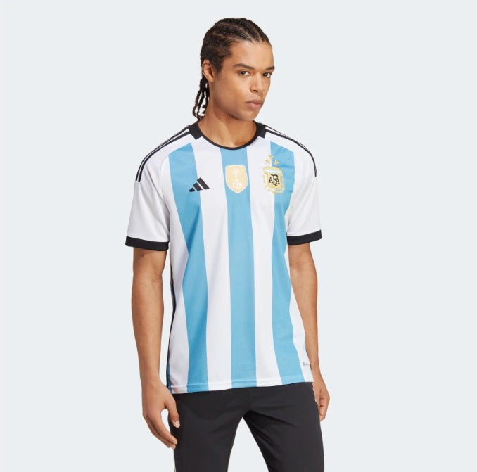 Jersey de local de Argentina Campeón del Mundo 2022, vista frontal completa mostrando los bastones albicelestes, escudo con 3 estrellas y parche FIFA.