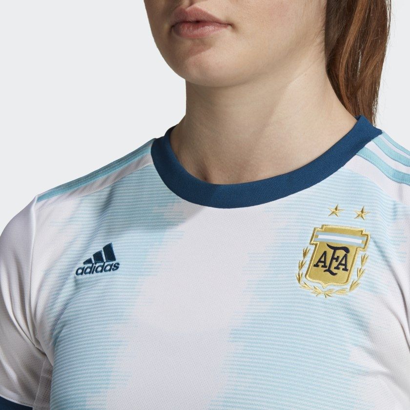 Primer plano de escudo oficial de la Asociación del Fútbol Argentino AFA con estrellas bordadas sobre tejido blanco inmaculado