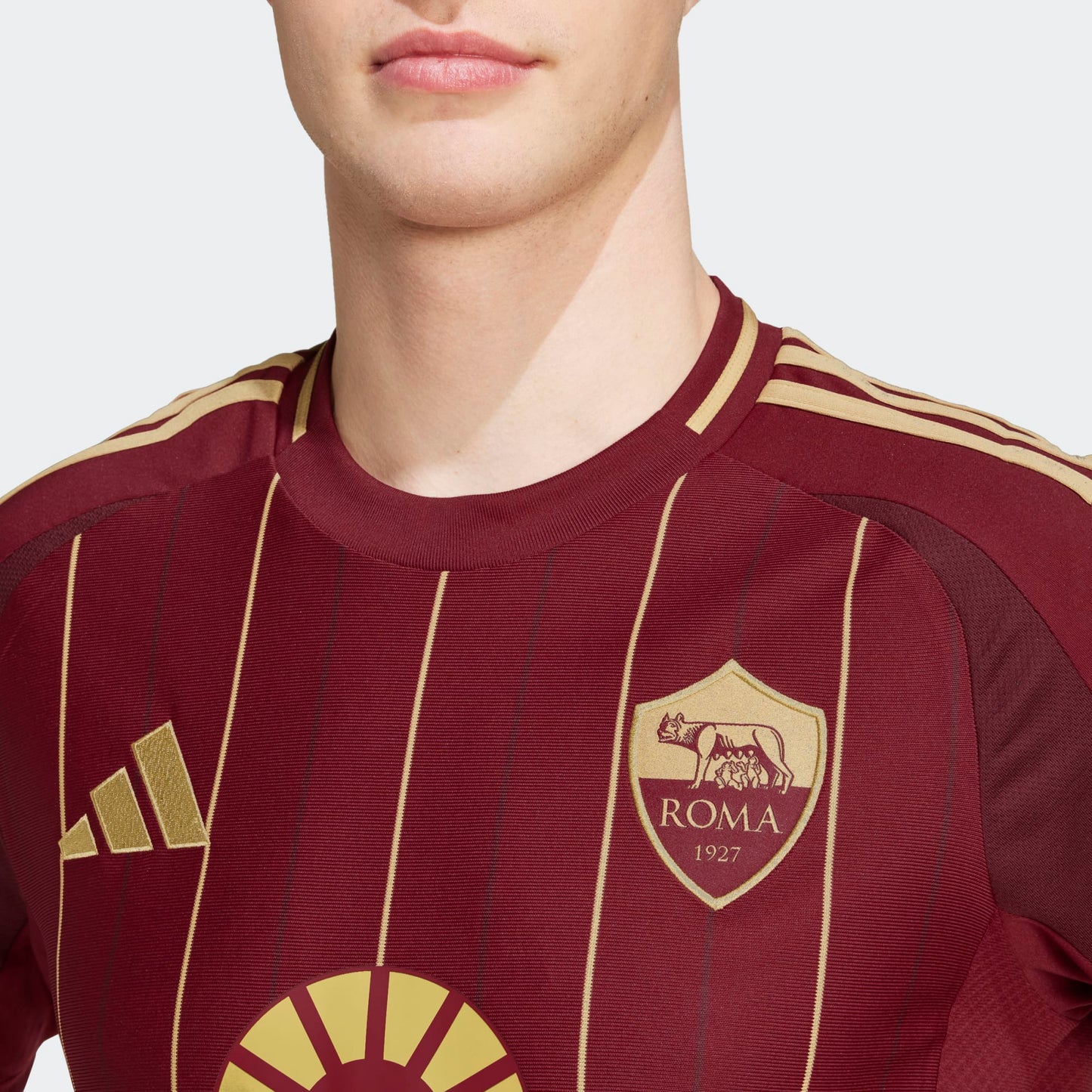 Detalle del escudo bordado de la AS Roma y el logotipo de Adidas en color dorado sobre el fondo granate profundo, resaltando la calidad premium de las aplicaciones y la heráldica del club, en Futbol90MX