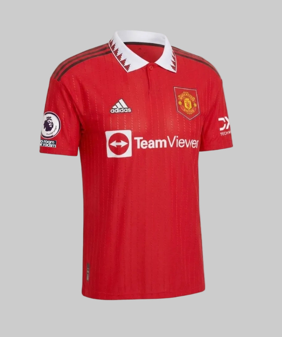 Ángulo lateral del jersey Authentic Match Manchester United 2022/23 mostrando la caída del tejido profesional y los parches de competencia Premier League.