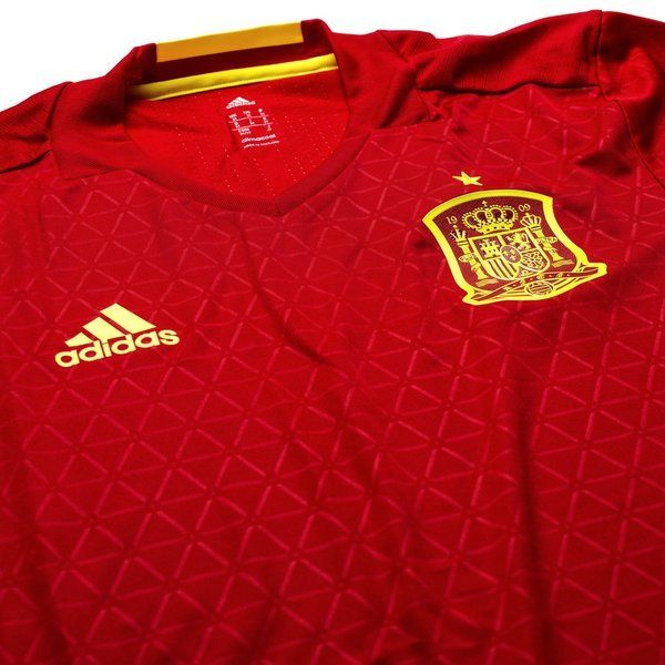 Escudo de la selección española y logo de Adidas aplicados mediante calor (termotransferencia) para minimizar el peso, característico de la versión de juego profesional, solo en Futbol90MX