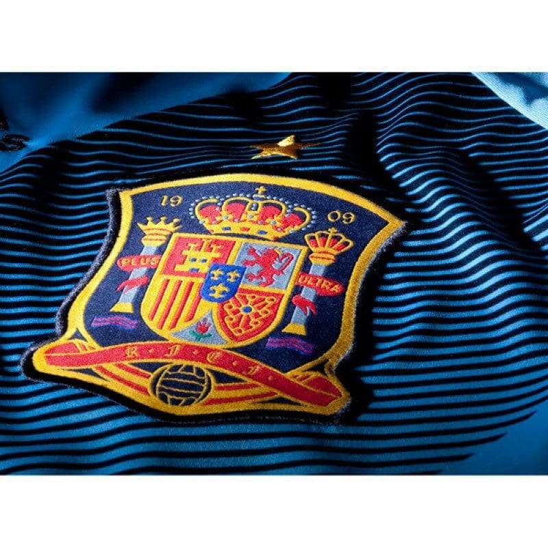 Primer plano del escudo de la Selección Española (RFEF) bordado con la estrella dorada de Campeón del Mundo y logotipo de Adidas centralizado.
