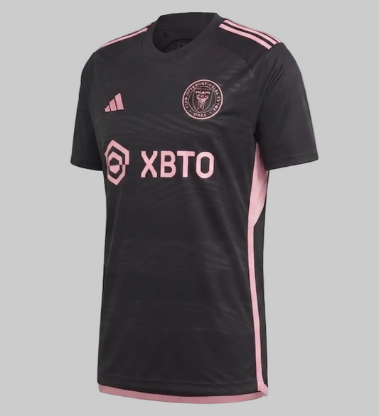 Vista angulada del jersey Inter Miami Visita 2023/24 (código HI1888), mostrando el escudo circular del club y el logo Adidas en rosa brillante sobre tejido técnico negro, disponible en Futbol90MX
