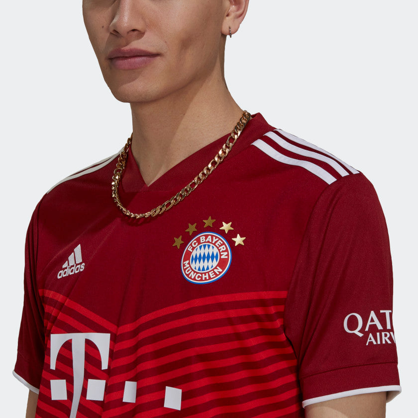 Primer plano ampliado del escudo del FC Bayern München con las cinco estrellas doradas de campeonato bordadas en el pecho del jersey de local UCL 2021/22 de Kimmich, stock Futbol90MX