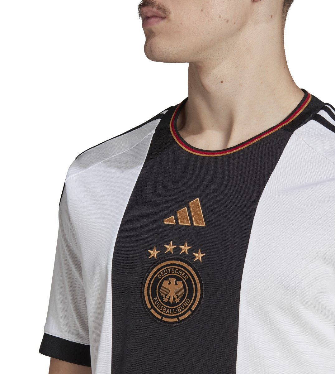Acercamiento al escudo de Alemania con 4 estrellas y al logo de adidas, bordados, cuello redondo con colores de la bandera alemana.