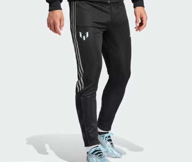 Vista de medio cuerpo de un modelo portando los pants de entrenamiento adidas Lionel Messi 2023 (Ref. IJ4943) con el logotipo personal del jugador y las tres franjas características en color claro sobre fondo negro, en Futbol90MX