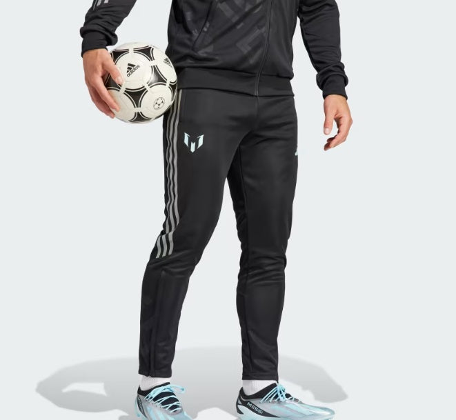 Detalle en primer plano de los pants de entrenamiento adidas Lionel Messi 2023 (Ref. IJ4943), mostrando el logotipo del GOAT en la pierna derecha, las tres franjas laterales y el modelo portando un balón clásico, disponible en Futbol90MX