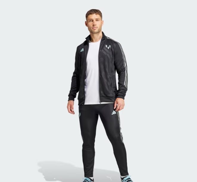 Modelo de cuerpo entero vistiendo el conjunto completo de chamarra y pants de entrenamiento adidas Lionel Messi 2023 (Ref. IJ4943), sosteniendo un balón histórico en la Historical Archive Boutique de Futbol90MX