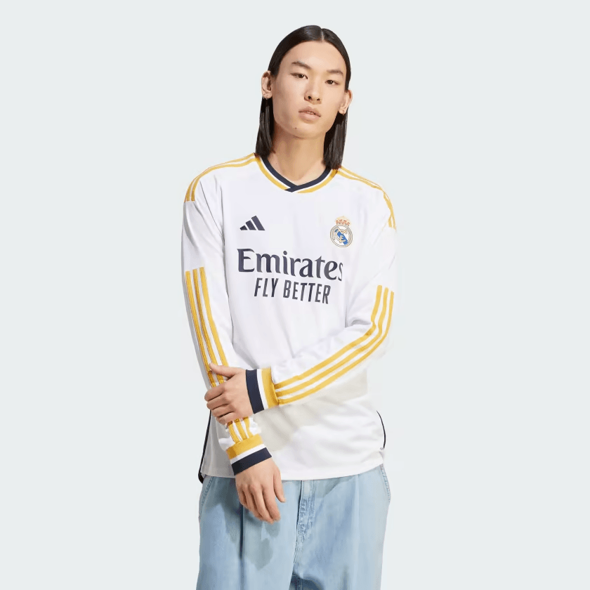 Modelo exhibiendo el jersey Adidas Real Madrid de manga larga de casa UCL 2023/24 (Ref. IB0018) de Modric con detalles dorados y azul marino en Futbol90MX
