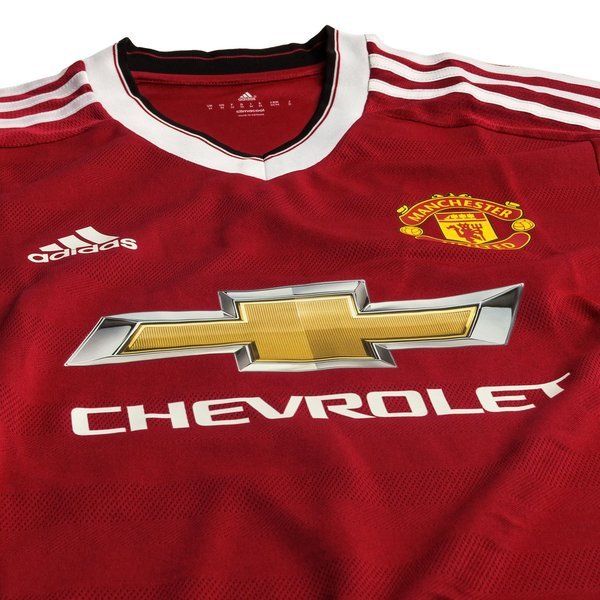 Primer plano del pecho del jersey authentic match de local del Manchester United 2015/16 (Ref. AC1415), destacando el patrocinador central Chevrolet en acabado metálico, el escudo del club y el logotipo de Adidas, todo sobre el tejido de malla de rendimiento profesional, stock Futbol90MX