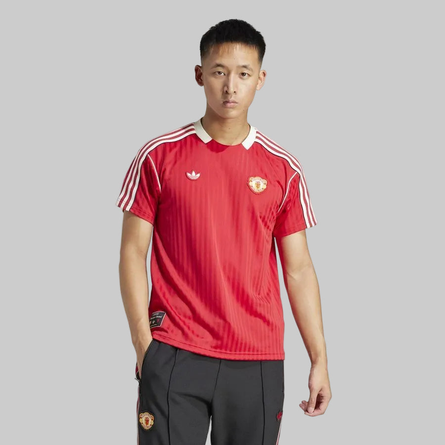 Modelo vistiendo el jersey Adidas Manchester United Icon (Ref. JF0386) de frente, destacando el ajuste de estilo de vida, el cuello retro y el tejido con rayas verticales tonales en Futbol90MX