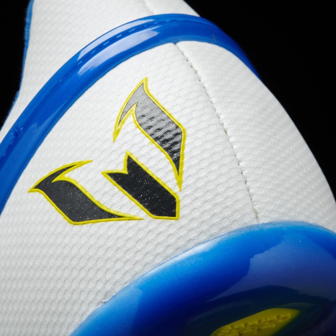 Detalle de los logotipos institucionales en el talón y lateral de los zapatos adidas Messi 15.1 FG juveniles (Ref. S81491) de Futbol90MX