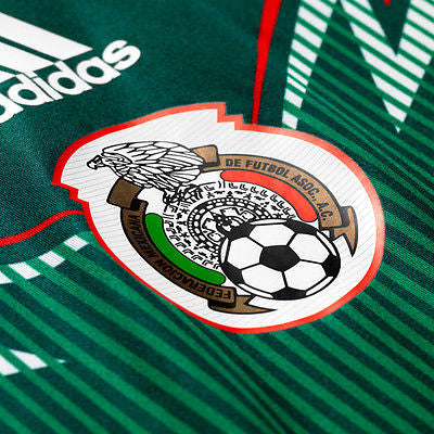Primer plano del escudo termosellado de la Selección Mexicana sobre el patrón gráfico frontal del jersey Adizero Brasil 2014 (Art. G86986) en Futbol90MX