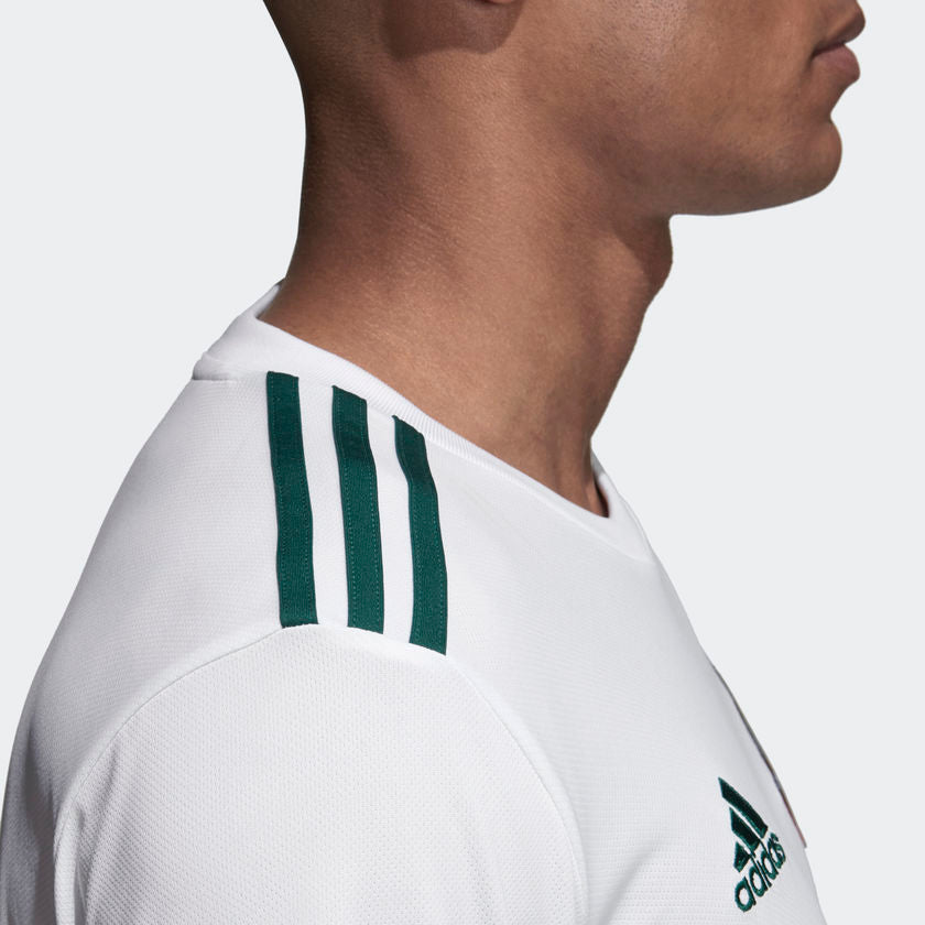 Las tres franjas icónicas de Adidas en color verde bosque cosidas sobre los hombros del jersey de visitante de México.