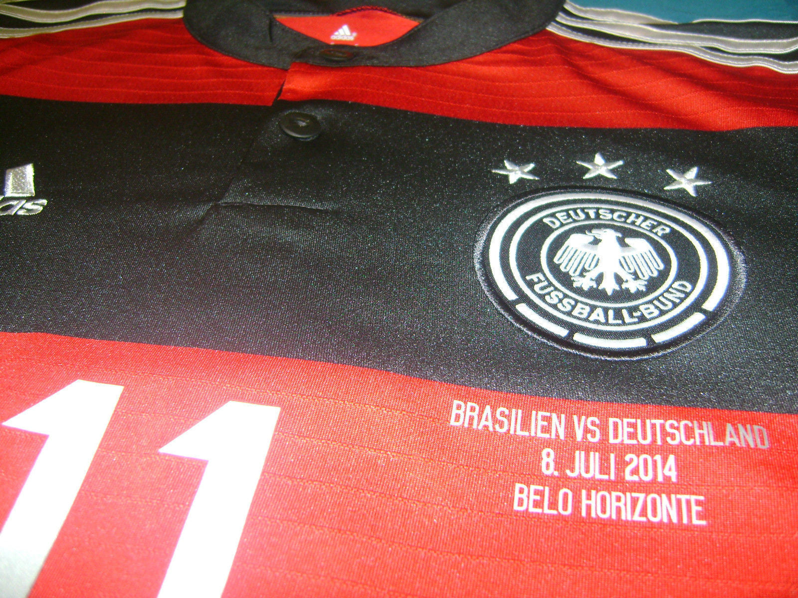 Acercamiento al pecho del jersey Adidas G74520 con el escudo oficial bordado de la DFB y el texto de juego termoaplicado Brasilien vs Deutschland 8.7.2014. stock Futbol90MX