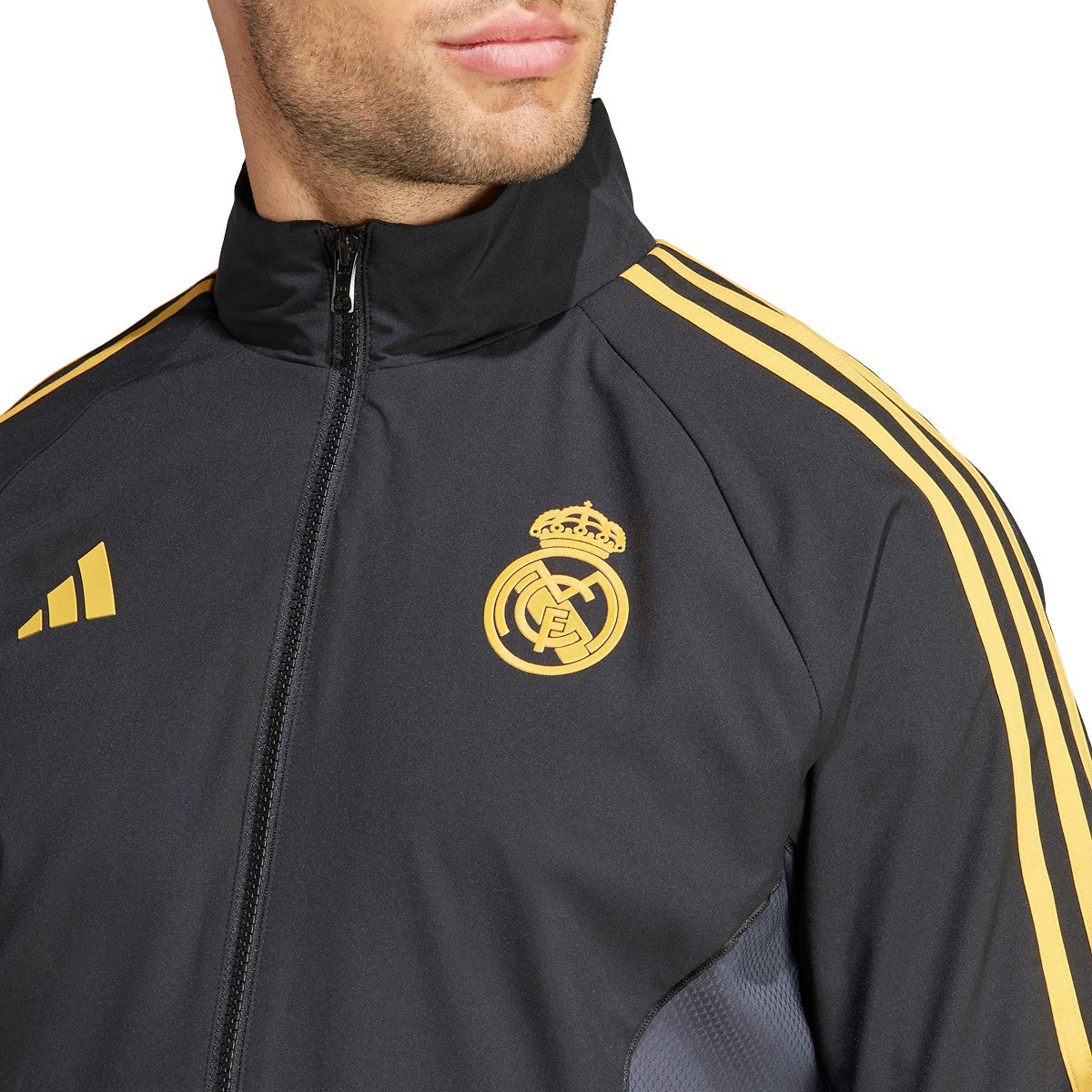 Primer plano del escudo del Real Madrid y logotipo Adidas en acabado dorado mate de alta densidad, colección europea.