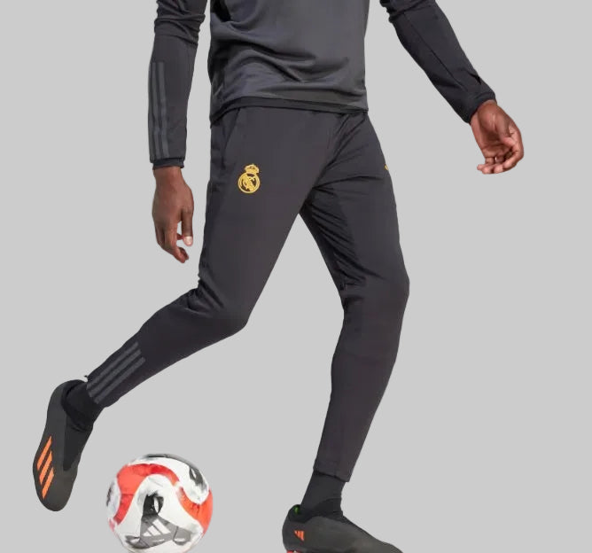 Vista lateral de los pants de entrenamiento Real Madrid 2023/24 mostrando el diseño aerodinámico y las icónicas franjas de Adidas.