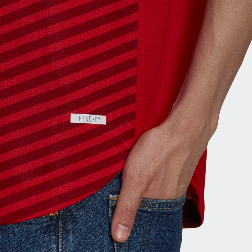 Primer plano del dobladillo inferior del jersey authentic match Bayern Munich FC local UCL 2021-22 de jugador (GM5308), resaltando la etiqueta dorada de autenticidad y el emblema de la tecnología de alto rendimiento Adidas HEAT.RDY, stock Futbol90MX