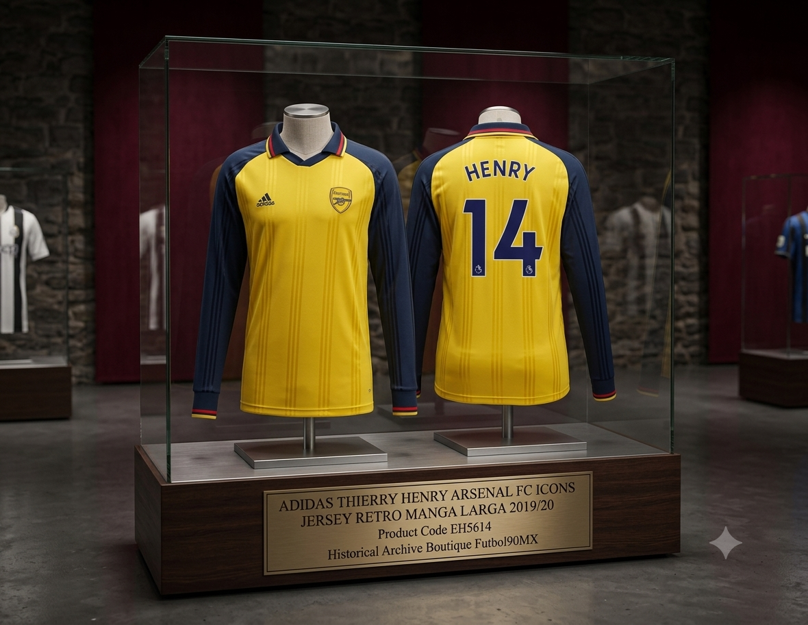 Una vitrina de exhibición de museo profesional que contiene dos camisetas idénticas del Adidas Thierry Henry Arsenal FC Icons de manga larga en amarillo y azul marino. La exhibición se encuentra en un entorno similar a un museo bien iluminado con otras exhibiciones en el fondo. Una placa de bronce en la base de la exhibición dice: "ADIDAS THIERRY HENRY ARSENAL FC ICONS JERSEY RETRO MANGA LARGA 2019/20, Código de producto EH5614, Historical Archive Boutique Futbol90MX". Las camisetas se muestran por delante 