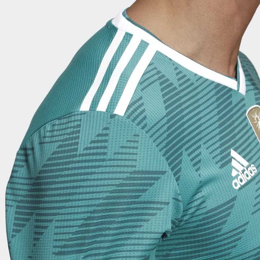 Vista detallada del panel de hombros con las tres franjas icónicas de Adidas y el patrón gráfico de líneas de velocidad característico del modelo away 2018.