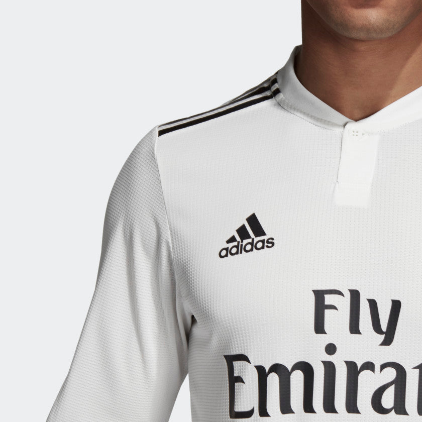 Primer plano de la parte superior del jersey de Kroos de local Real Madrid UCL 2018/19, resaltando el diseño del cuello, la aplicación del logo Adidas y el patrocinio principal "Fly Emirates" en la versión Authentic Match, stock Futbol90MX