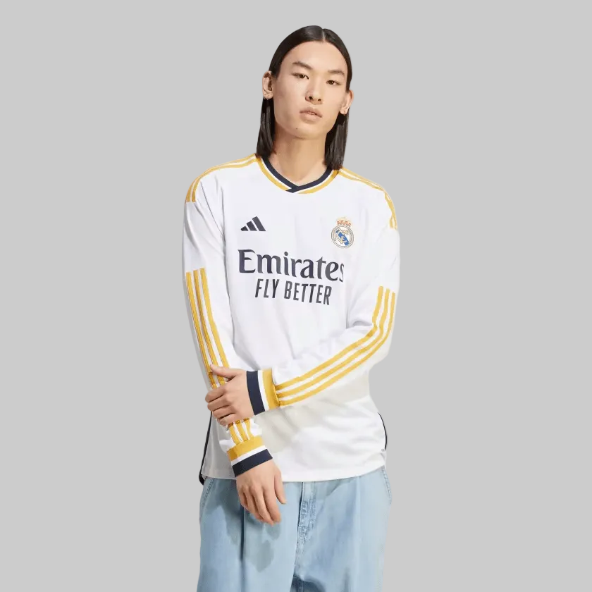 Modelo exhibiendo el jersey Adidas Real Madrid de manga larga de casa UCL 2023/24 de Vini Jr (Ref. IB0018) con detalles dorados y azul marino en Futbol90MX