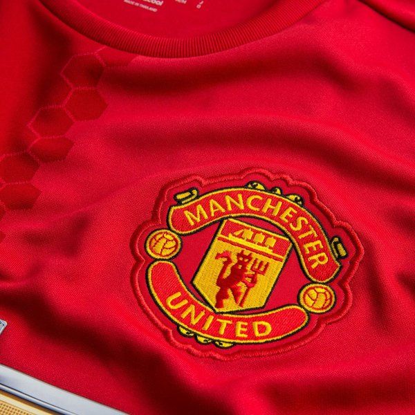 Primer plano del escudo bordado del Manchester United y detalle de la trama hexagonal sobre el tejido rojo del jersey local 2016/17 de Ibrahimovic (Ref. AI6720) en Futbol90MX