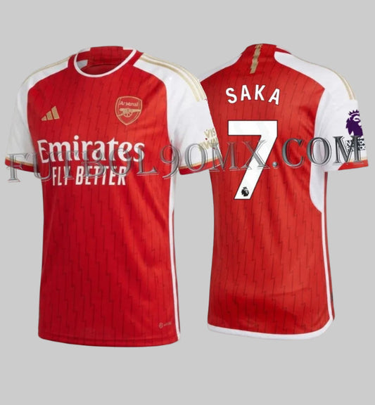 Vista dual del Jersey Adidas  Authentic Match de Bukayo Saka Local (Arsenal FC 2023/24). Muestra la personalización oficial de la Premier League con el nombre 'SAKA' en la parte superior y el dorsal '7' grande, ambos en blanco con borde negro, sobre el tejido rojo texturizado, codigo HR6931, disponible en Futbol90MX.