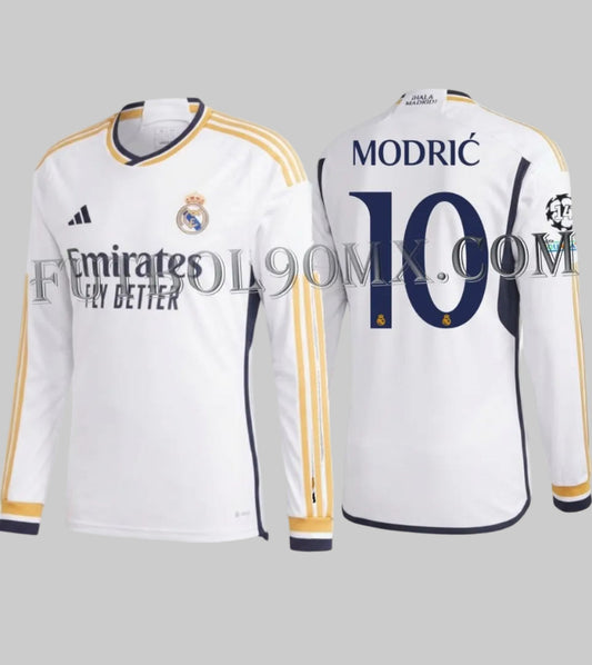 Vista frontal y posterior del jersey Adidas Luka Modric Real Madrid de manga larga para UEFA Champions League de casa 2023/24 (Ref. IB0018) con tipografía oficial #10 y parches continentales, disponible en la Historical Archive Boutique de Futbol90MX