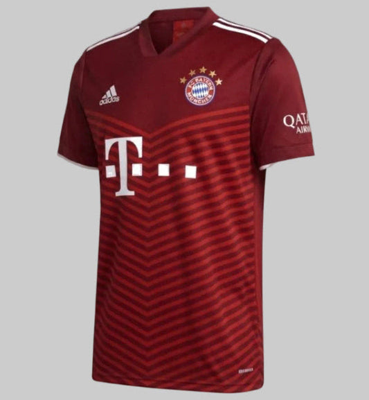 Vista en ángulo de tres cuartos frontal del jersey de local Adidas del FC Bayern München 2021/22, destacando la estructura del cuello en V, el escudo con las cinco estrellas doradas y el diseño de chevrones en el torso, codigo GM5313, disponible en Futbol90MX
