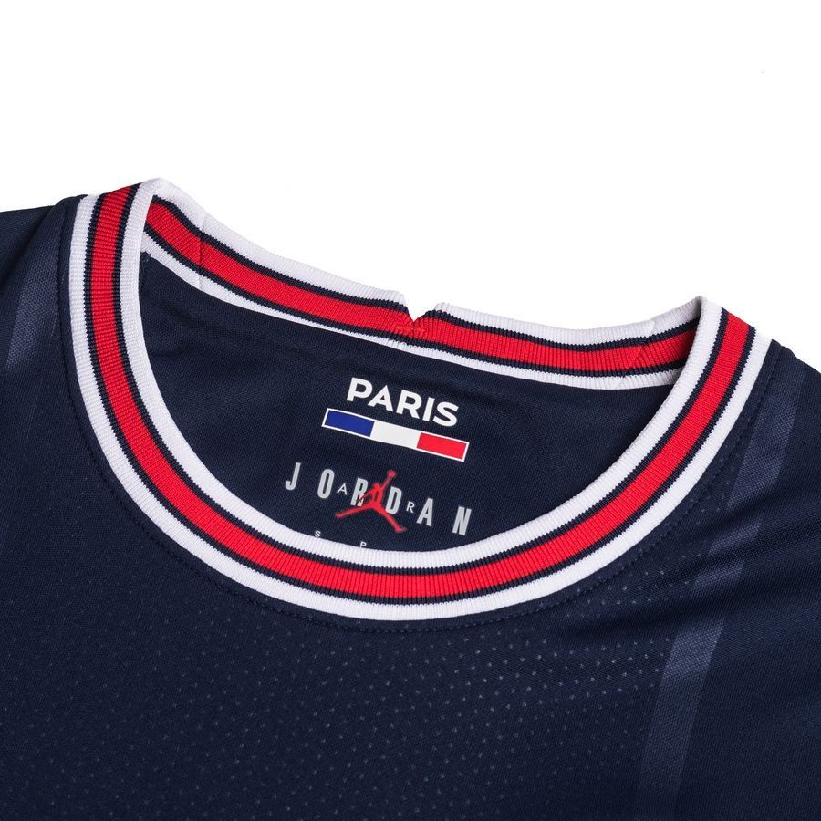 Detalle del cuello del jersey Jordan x Lionel Messi PSG UCL 2021/22, mostrando el ribete tricolor (azul, blanco y rojo), la inscripción "PARIS" sobre la bandera francesa y el logotipo Jumpman integrado en el diseño de la etiqueta interior, reflejando la autenticidad de la Historical Archive Boutique.