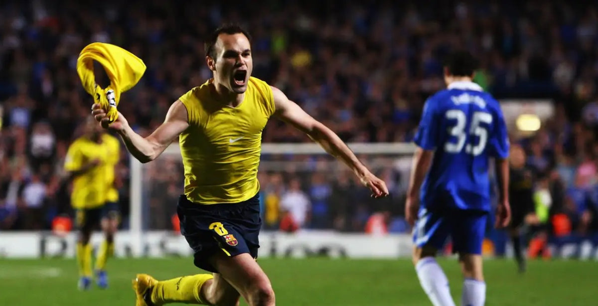 Andrés Iniesta quitándose el jersey amarillo del FC Barcelona visitante 2008/09 (Ref. 286787-760) en la icónica celebración del gol en Stamford Bridge frente a defensas rivales en Futbol90MX
