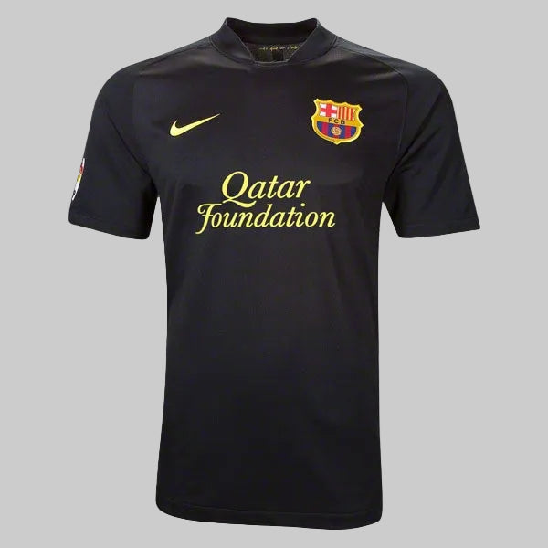 Vista frontal del jersey de visita Nike FC Barcelona 2011/12 en color negro, con patrocinio de Qatar Foundation en dorado y escudo bordado del club. Versión oficial de archivo histórico.