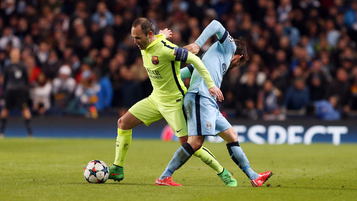 Andrés Iniesta disputando el balón durante un partido de UEFA Champions League portando el jersey tercero 2014/15 (Ref. 631192-711) en Futbol90MX