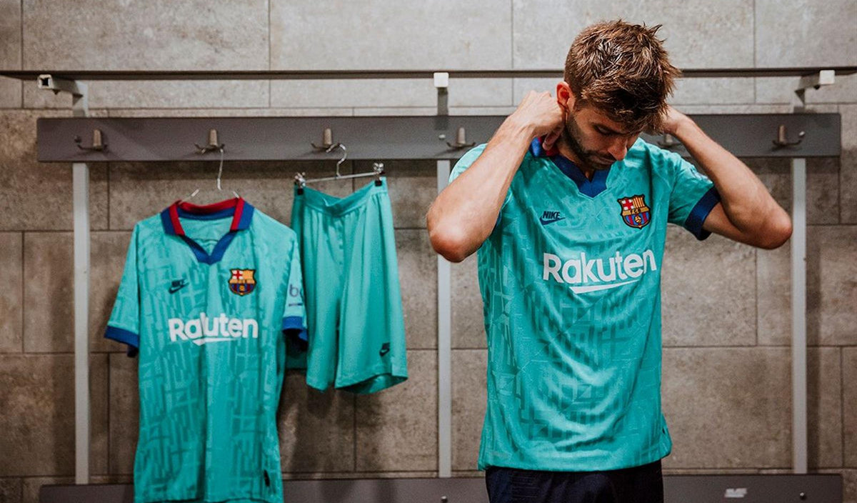 Fotografía de la campaña oficial del FC Barcelona mostrando el Nike tercer kit turquesa 2019/20 colgado en el vestidor junto a un jugador vistiendo la equipación completa (Ref. AT0029-310)