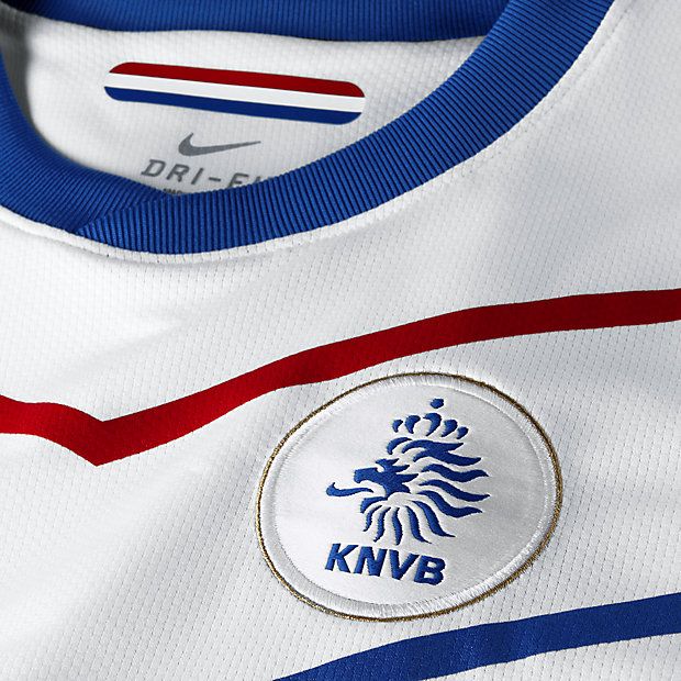 Primer plano del escudo bordado de la KNVB y el diseño geométrico en 'V' azul y rojo sobre la base blanca del jersey de visita 2010/11