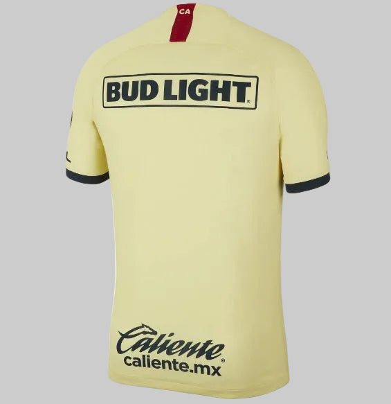 Vista posterior del jersey de local Nike Club América 2019/20 mostrando los patrocinios oficiales de Bud Light y Caliente.mx en color azul marino, además de las siglas CA en la parte superior del cuello (Art. AJ5527-707), stock Futbol90MX