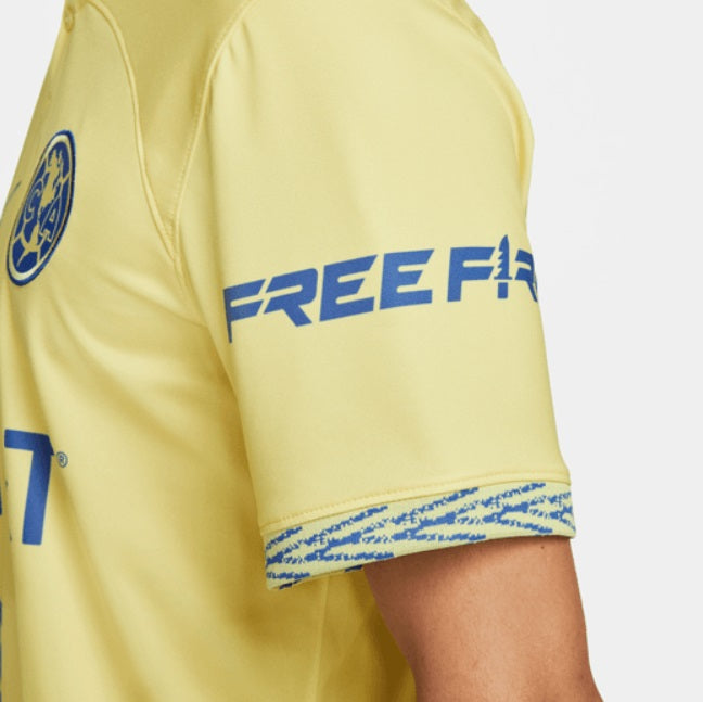 Vista angular izquierda que muestra el parche del patrocinador "Free" en la manga y la estructura del tejido técnico.