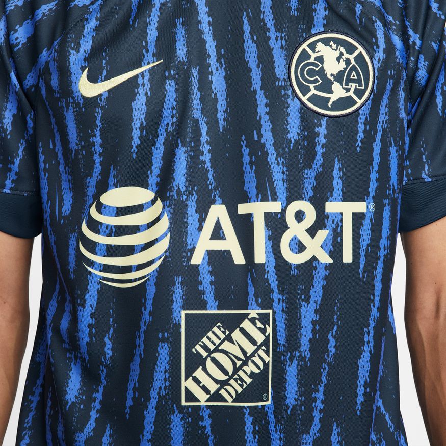Detalle del logo de AT&T termotransferido sobre el patrón gráfico pixelado, validando la aplicación de grado comercial de la temporada 22/23.