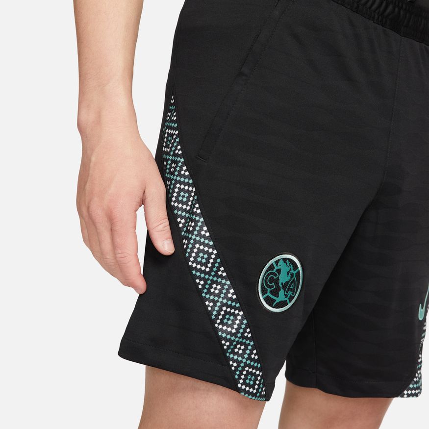 Primer plano del patrón de mosaico geométrico en los costados de los shorts Strike Club América, combinando tonos verde jade y crema.