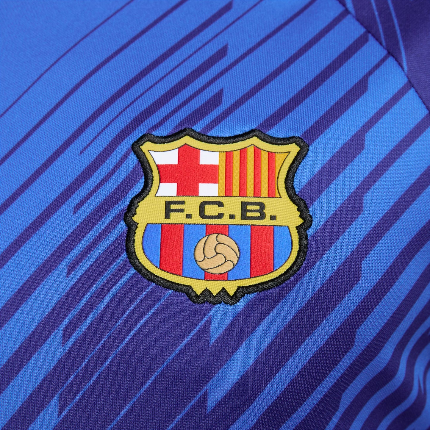 Primer plano del escudo del FC Barcelona sobre tejido técnico de alto rendimiento.