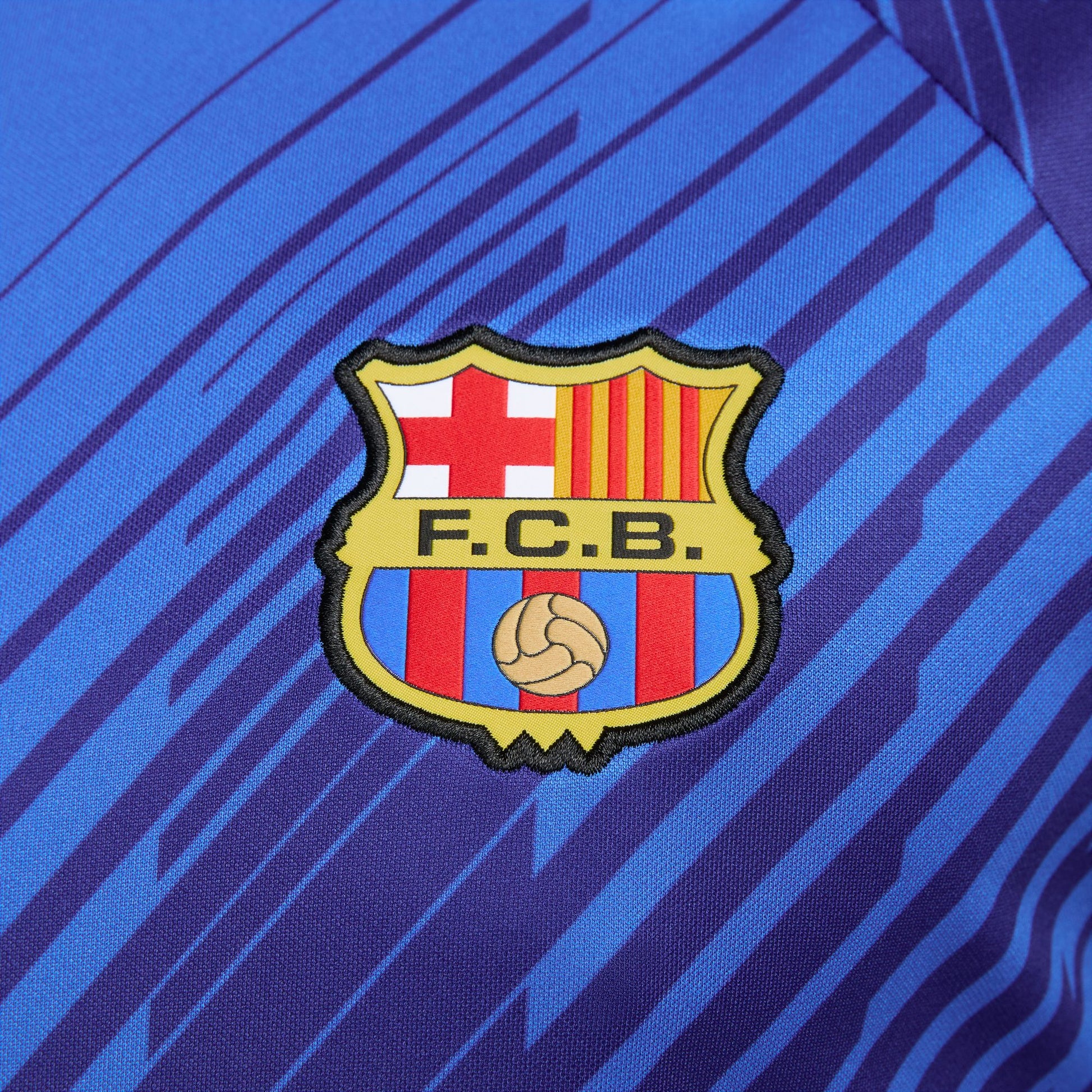 Primer plano del escudo del FC Barcelona sobre tejido técnico de alto rendimiento.