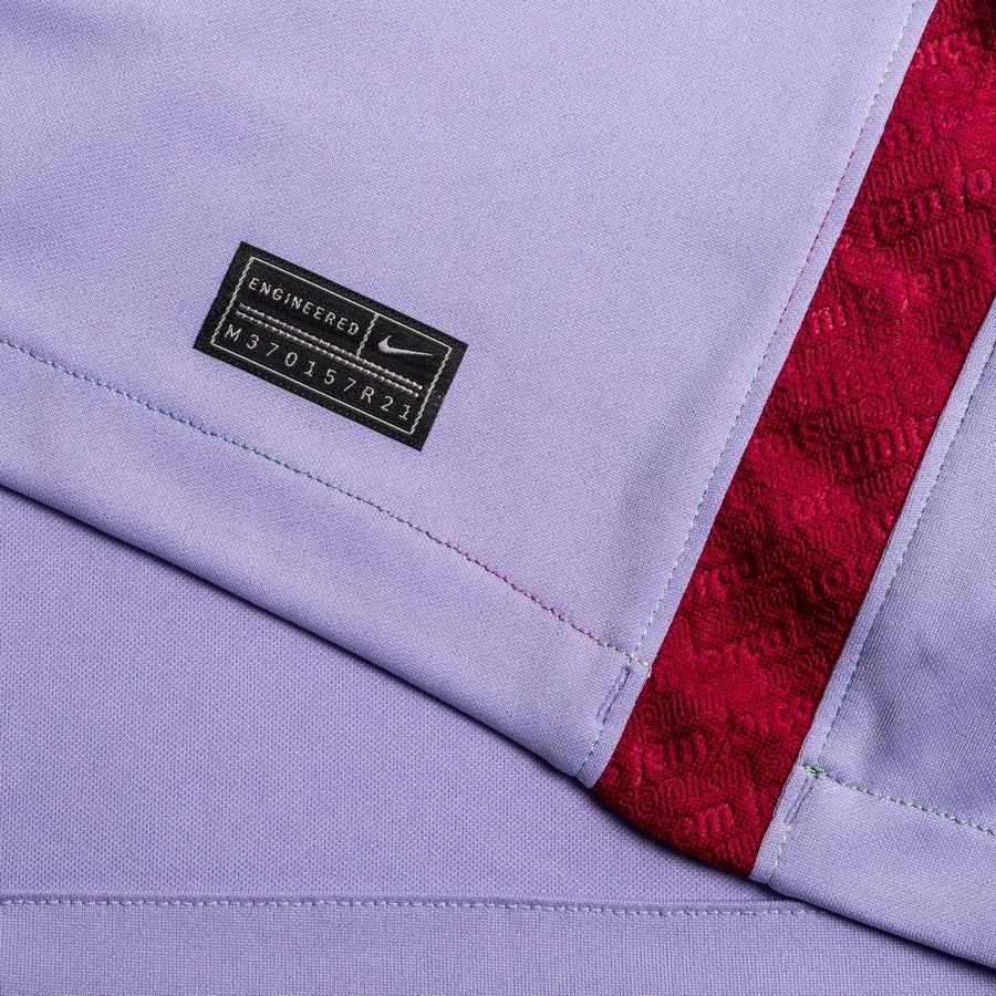 Primer plano de la etiqueta de autenticidad Engineered con código de serie en el dobladillo inferior del jersey y detalle de la franja lateral en tono grana y azul aplicada en el costado del jersey de visita Nike FC Barcelona 2021/22 (CV7890-581) en Futbol90MX