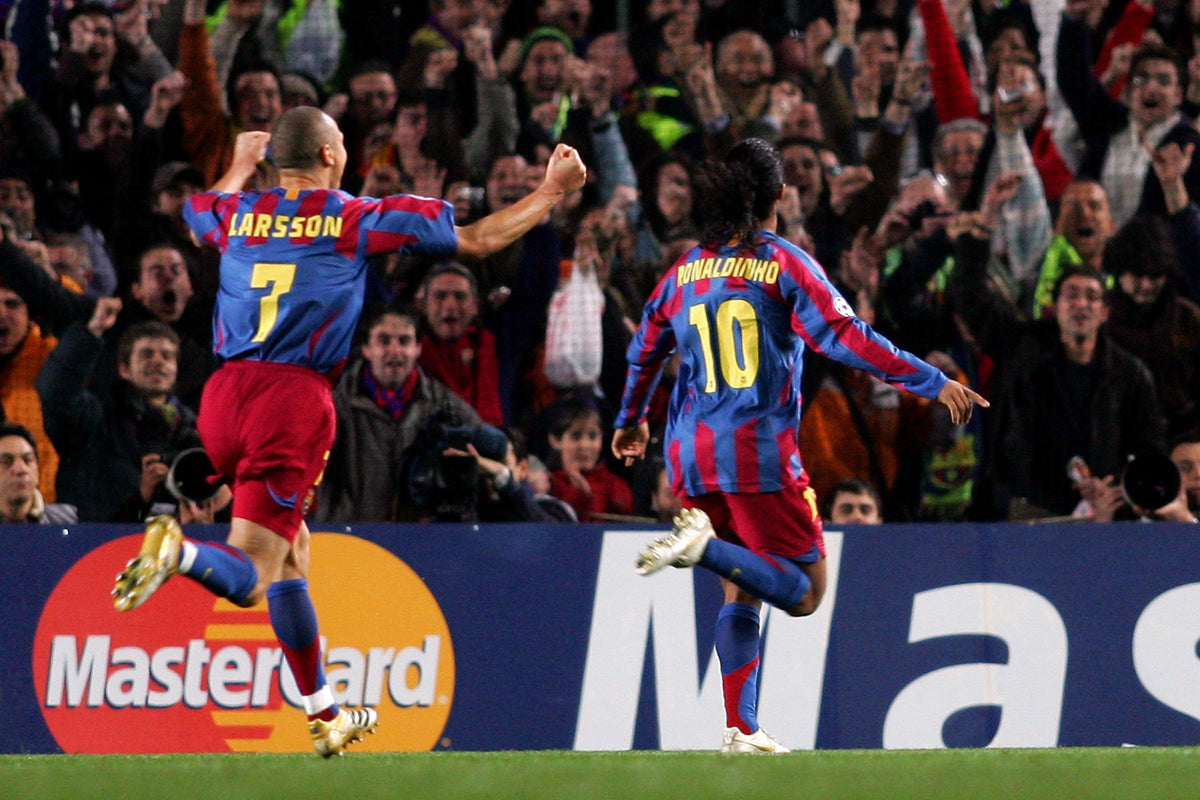 Henrik Larsson con el dorsal #7 y Ronaldinho con el #10 celebrando de espaldas durante un partido del FC Barcelona en Futbol90MX