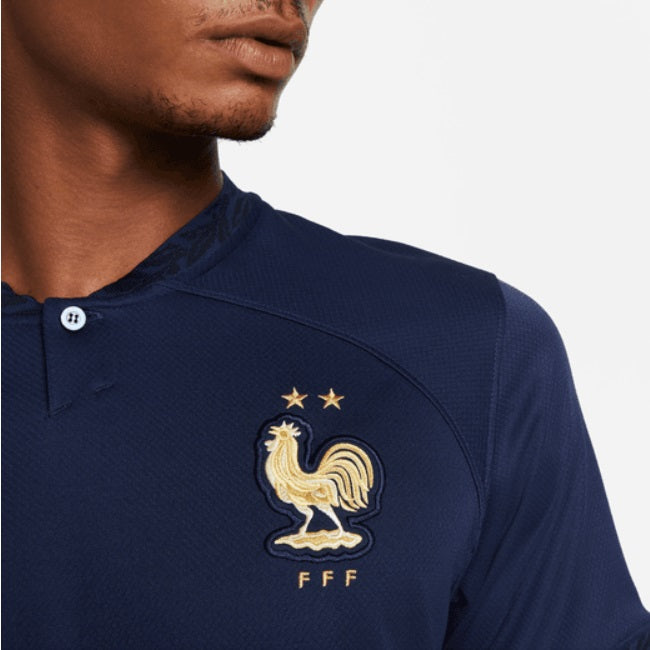 Primer plano del escudo de la Federación Francesa de Fútbol bordado en acabado dorado metálico sobre el tejido azul marino del Jersey de Mbappe de Francia Local Mundial 2022 en Futbol90MX
