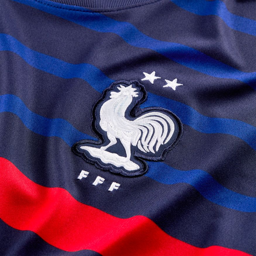 Escudo de la FFF con dos estrellas y parche blanco de Campeón del Mundo FIFA 2018 en jersey Francia 2020.