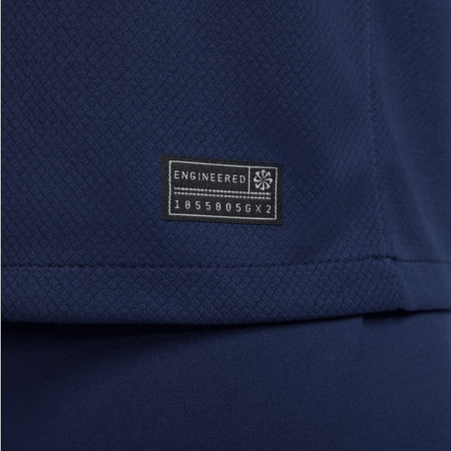 Acercamiento a la etiqueta de autenticidad en el dobladillo inferior, validando la tecnología Nike Dri-FIT y el código de fábrica DN0665-410.