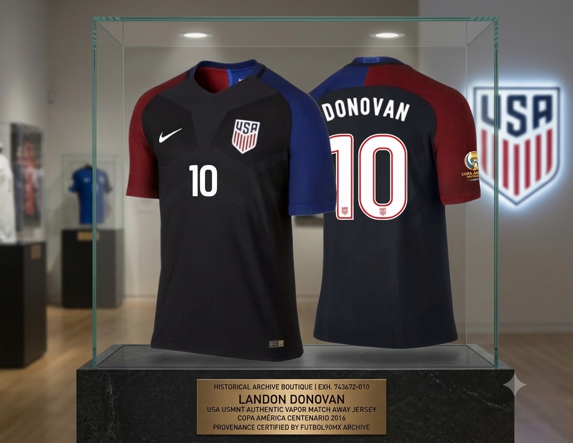 Imagen de calidad museo del jersey Authentic Vapor Match de visitante USA 2016 de Landon Donovan, exhibido en una vitrina con iluminación profesional. Los dorsales muestran el detalle correcto de la línea interna en color rojo. Una placa conmemorativa certifica la procedencia: 'HISTORICAL ARCHIVE BOUTIQUE | EXH. 743672-010 | LANDON DONOVAN | USA USMNT AUTHENTIC VAPOR MATCH AWAY JERSEY | COPA AMÉRICA CENTENARIO 2016 | PROVENANCE CERTIFIED BY FUTBOL90MX ARCHIVE'."
